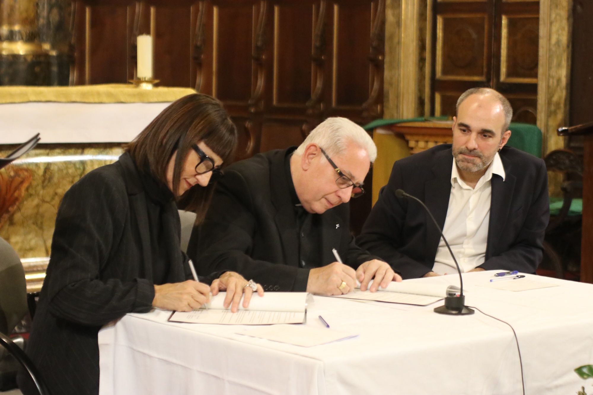 Núria Sempere i Ferran Colàs signen el conveni en presència de Juan de la Rubia.